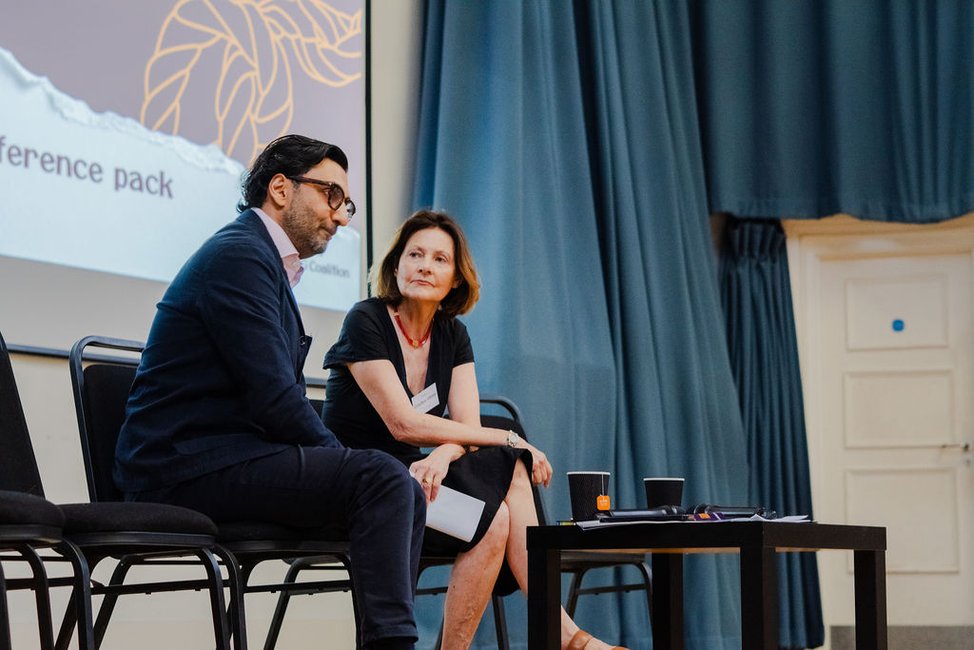 A man and woman sitting on the stage in conversation
